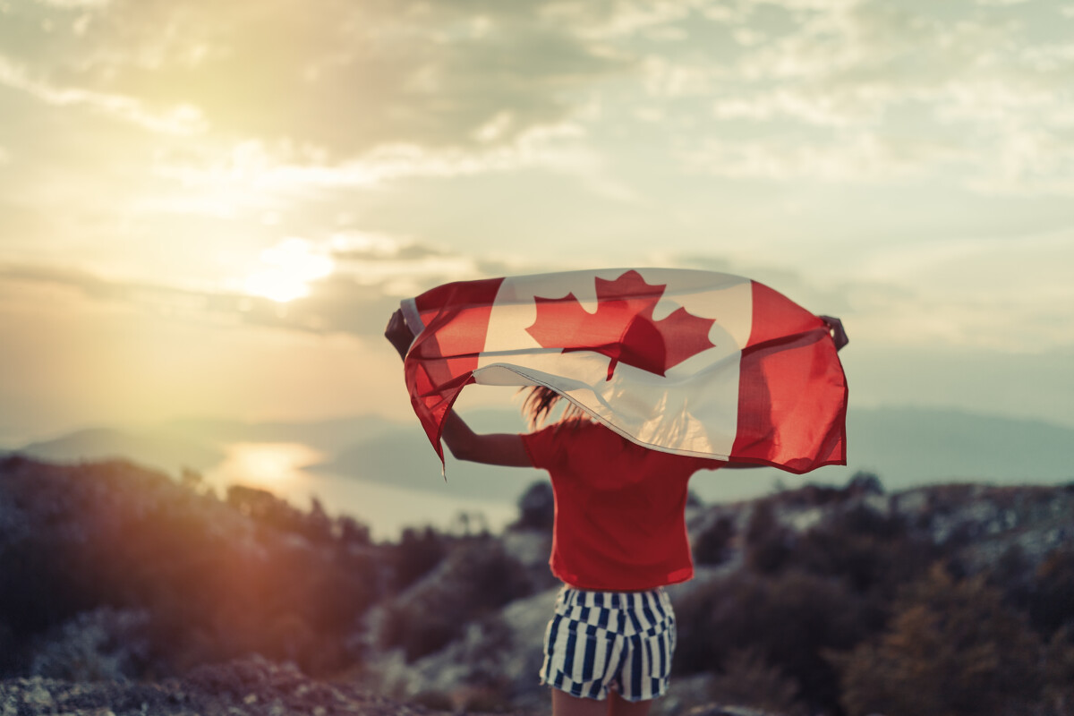 Happy child teenage girl waving the flag of Canada while running